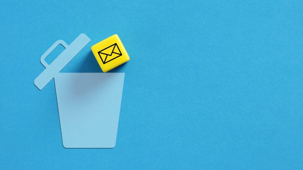 Yellow cube with email symbol falling into blue trash can stock photo